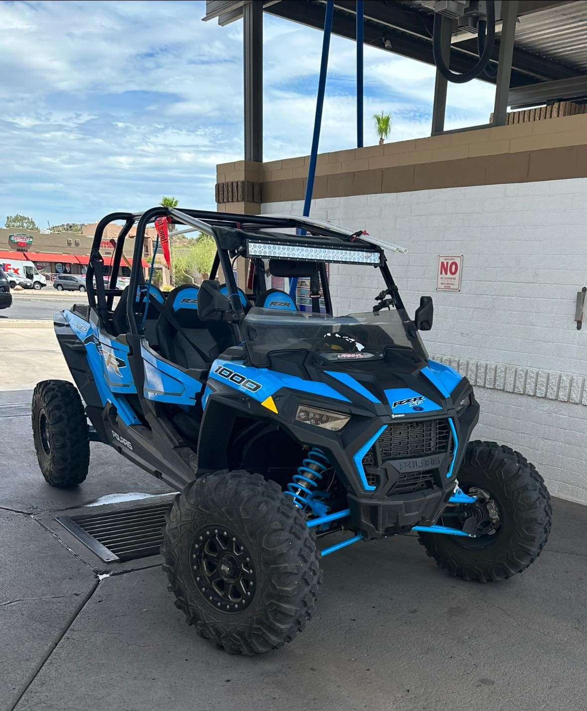 Blue and black Polaris RZR 1000 off-road vehicle parked at a car wash station.