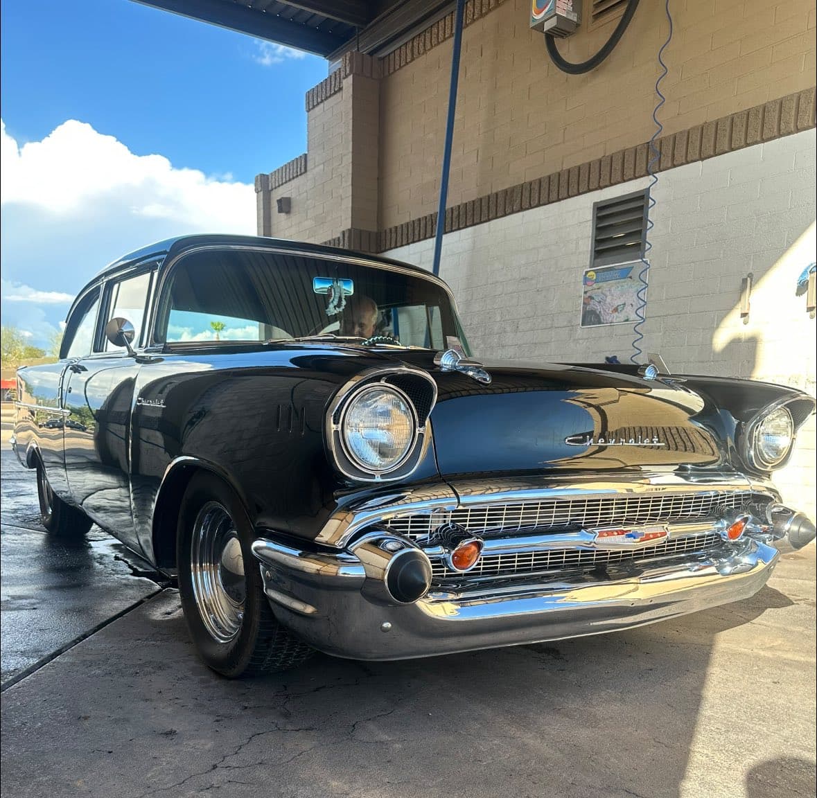 Shiny black vintage Chevrolet with chrome bumpers and grille parked at a car wash.