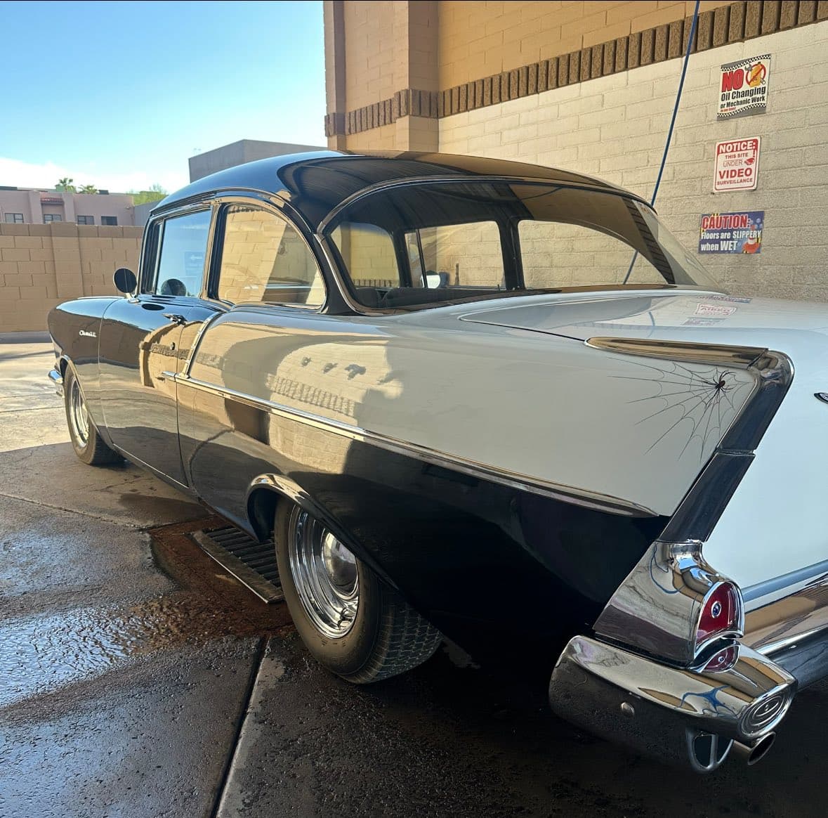 Two-tone black and white classic car with spider web pinstriping in a car wash.